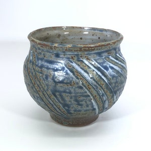 May include: A blue and brown ceramic bowl with a textured, swirling design. The bowl has a wide base and a rounded shape.