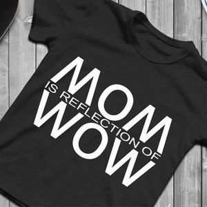 Könnte beinhalten: Schwarzes T-Shirt mit weißem Text, der "MOM IS REFLECTION OF WOW" lautet.
