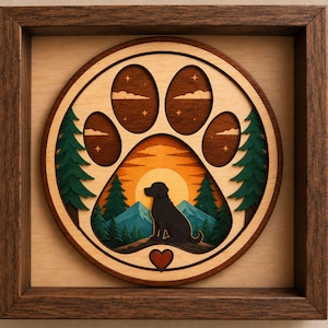 May include: A layered wooden wall art piece in a dark brown square frame featuring a circular cutout shaped like a paw print. Inside the paw, a black dog silhouette sits before a yellow sun, blue mountains, green pine trees, and a starry sky.