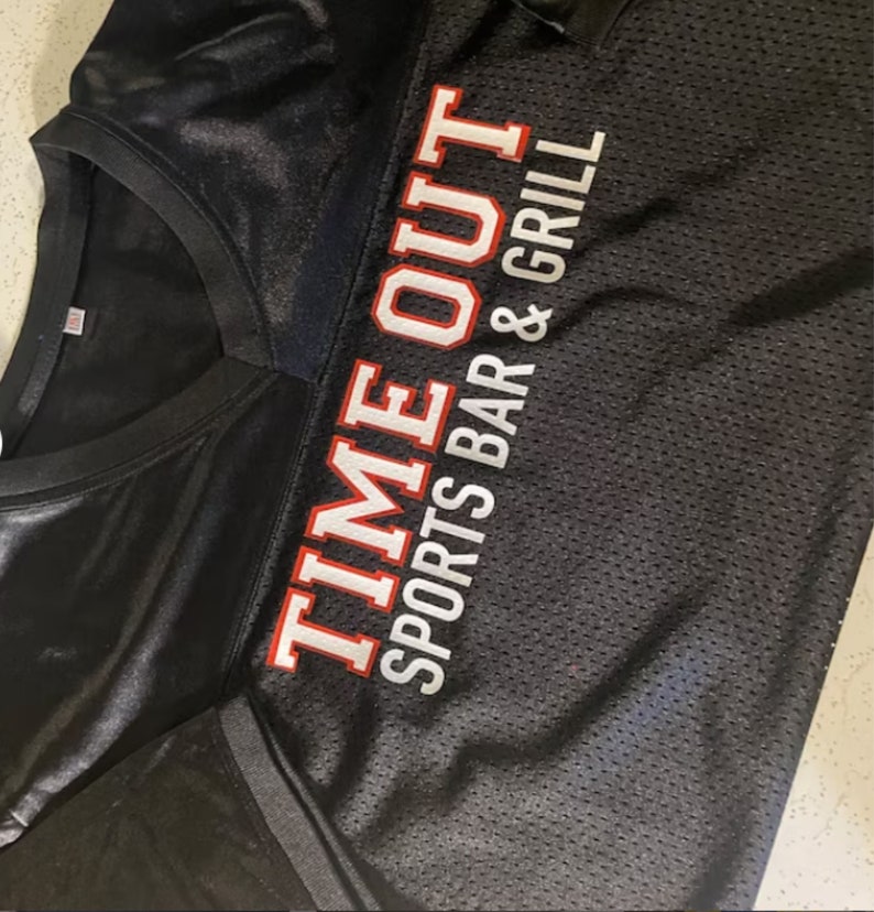 May include: Black jersey with white and red text that reads "TIME OUT SPORTS BAR & GRILL"