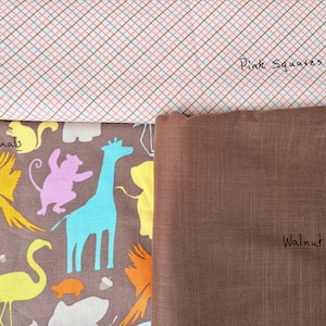 May include: A fabric assortment featuring three distinct patterns. The top fabric displays a pink and white plaid design with the text "Pink Squares." Below, a brown fabric is labeled "Walnut Brown." The bottom fabric showcases colorful animal illustrations.