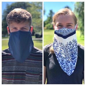 May include: Two people wearing face masks. One mask is solid navy blue, and the other is white with a blue floral pattern. Both masks are triangular in shape, covering the nose and mouth, with straps around the ears.