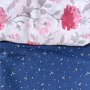 May include: Two fabric swatches. The top swatch is white with a floral pattern of pink and red flowers and gray leaves. The bottom swatch is navy blue with a pattern of white stars and yellow moons. Text on the top swatch says "Pale Beauty" and the bottom swatch says "Nighttime".