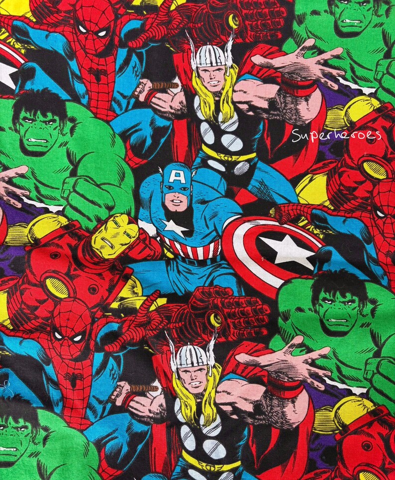 May include: A colourful fabric print showcasing various comic book superheroes. The design includes Captain America, Thor, Spider-Man, and the Hulk, with the word "Superheroes" visible. The characters are in their classic costumes, with bold colours and dynamic poses.