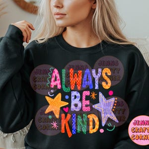 May include: Black sweatshirt with the words "ALWAYS BE KIND" in colorful, whimsical lettering. The design includes stars, hearts, and a smiley face. The sweatshirt also features the text "JENNS CRAFTY CORNER".