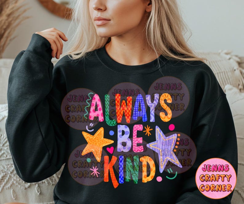 May include: Black sweatshirt with the words "ALWAYS BE KIND" in colorful, whimsical lettering. The design includes stars, hearts, and a smiley face. The sweatshirt also features the text "JENNS CRAFTY CORNER".