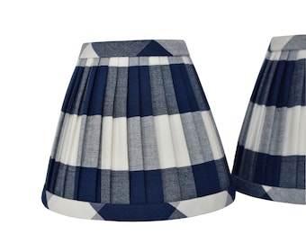 May include: Two blue and white gingham lampshades with pleated fabric. The lampshades are a classic style and would add a touch of farmhouse charm to any room.
