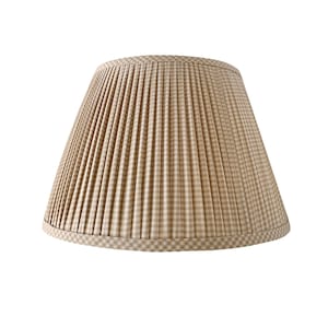 May include: A beige and white plaid lampshade with a pleated design. The lampshade has a classic, tapered shape and a decorative trim at the bottom. The fabric has a gingham pattern.