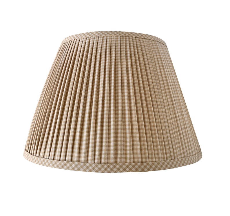 May include: A beige and white plaid lampshade with a pleated design. The lampshade has a classic, tapered shape and is trimmed with a matching plaid border. The fabric has a subtle texture, and the overall aesthetic is traditional and elegant.