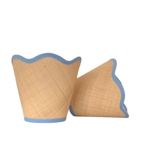 May include: Two woven lampshades with a scalloped edge and a light blue trim.