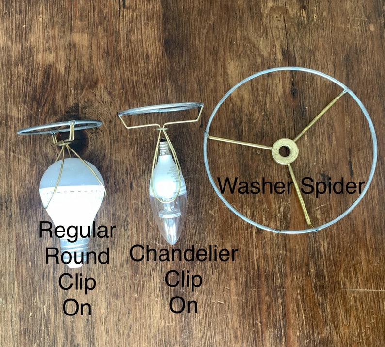 May include: Three lamp shade components are displayed against a wood background. The items include a regular round clip-on shade, a chandelier clip-on shade, and a washer spider. The text on the image reads "Regular Round Clip On", "Chandelier Clip On", and "Washer Spider".