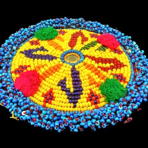 May include: A circular beaded design with a central mirror, surrounded by colourful beads in shades of yellow, red, orange, blue, green, and purple. The outer edge is trimmed with blue beads.