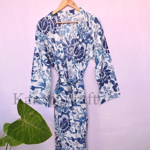 May include: A white cotton robe with a blue floral print. The robe has long sleeves and a tie belt.