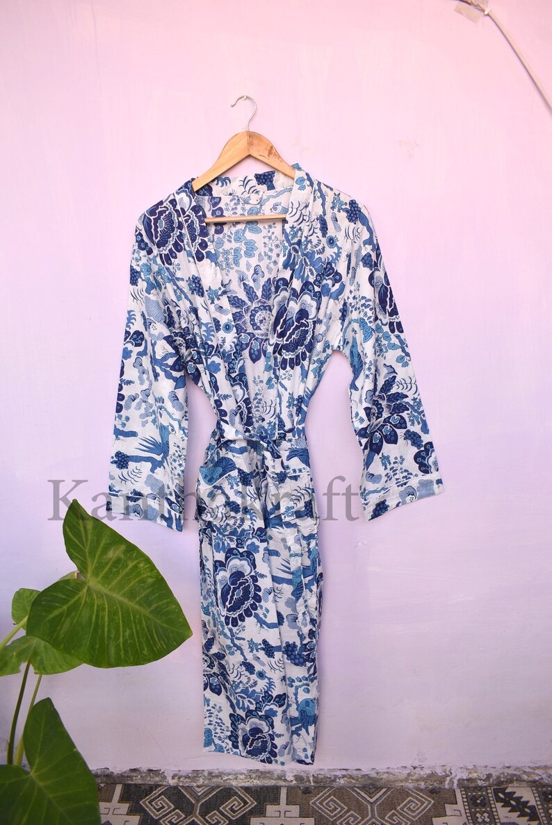 May include: A white cotton robe with a blue floral print. The robe has long sleeves and a tie belt.