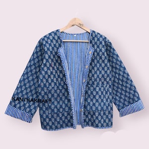 May include: A blue quilted jacket with a striped lining and a button closure. The jacket has a floral pattern and the text "KANTHAKRAFT" is visible on the left sleeve.