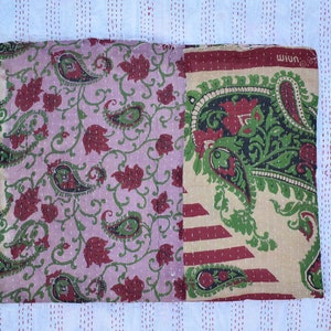 May include: A patchwork quilt made from vintage fabric with a paisley pattern in shades of pink, green, and red. The quilt is hand-stitched and has a unique, rustic look.