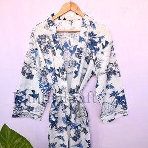 May include: White cotton robe with a blue floral print featuring birds and branches. The robe has a tie belt and long sleeves.