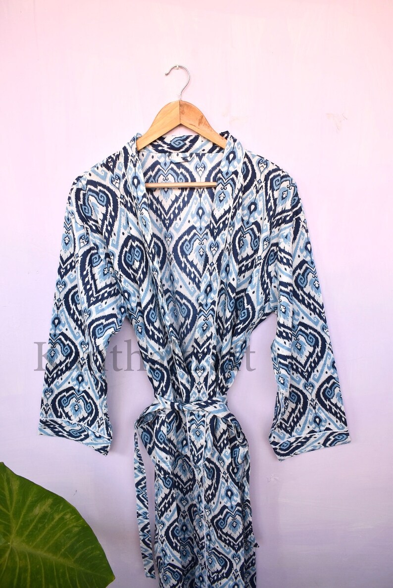 May include: A blue and white patterned cotton robe with a tie belt. The robe has a geometric design with a white background and blue accents.