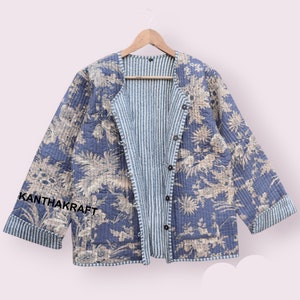 Peut inclure: Une veste matelassée bleue avec un imprimé floral et une doublure rayée. La veste a une fermeture à bouton et est étiquetée "KANTHAKRAFT" sur la manche.