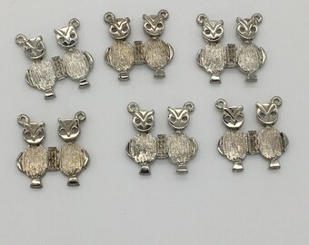 May include: Ten silver owl charms with detailed features. Each charm is a pair of owls facing each other.