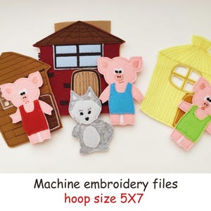 May include: A set of felt machine embroidery designs featuring three pigs in red, blue, and green outfits, a gray wolf, and three houses in brown, red, and yellow. The text reads: Machine embroidery files, hoop size 5X7 inches.