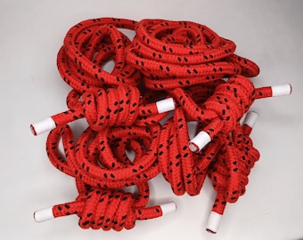 May include: A close-up of red and black rope with white tips. The rope is coiled and knotted.
