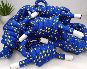 May include: A close-up of a pile of blue and yellow rope with white tips. The rope is made of a thick, braided material and has a dotted pattern.