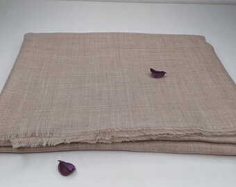 May include: A light brown pashmina shawl with a fringed edge. The shawl is folded in half and lying flat on a white surface.