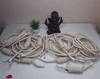 May include: A pile of white cotton rope with knots tied at the ends. The rope is arranged in a circular pattern.