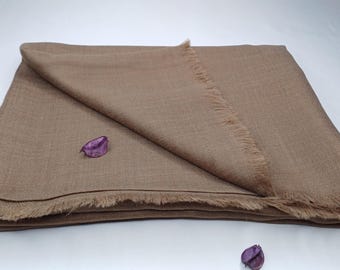 May include: A brown pashmina shawl with a fringed edge. The shawl is folded in half and laid flat on a white surface.