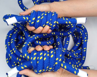May include: A blue and yellow rope with white ends. The rope is coiled and tied in a knot.