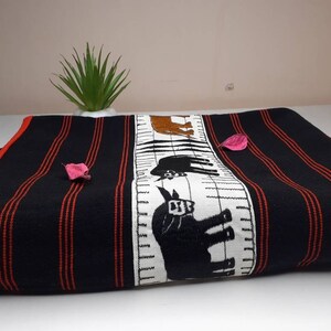 May include: Black and red striped fabric with a white panel featuring embroidered black animal silhouettes. The fabric is folded and displayed on a white surface.