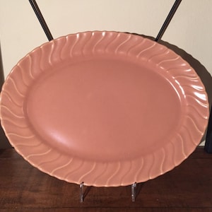 May include: A large, oval-shaped serving platter with a wavy, ribbed design. The platter is a light peach color.