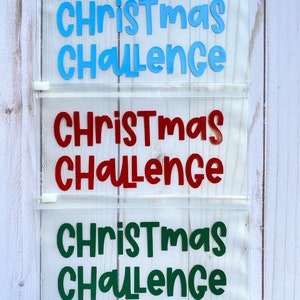 May include: Three clear plastic zippered pouches with the text "Christmas Challenge" in blue, red, and green lettering.
