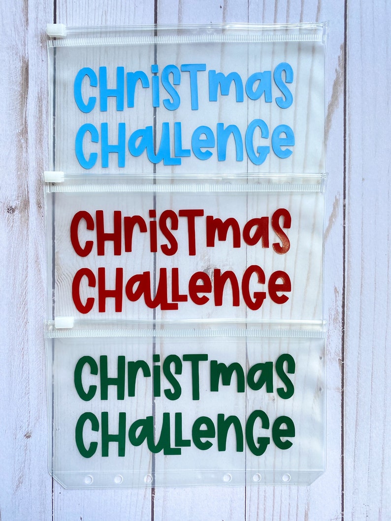 May include: Three clear plastic zippered pouches with the text "Christmas Challenge" in blue, red, and green lettering.