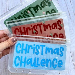 May include: Three clear plastic zipper pouches with different colored backgrounds and the text "Christmas" or "Christmas Challenge" in bold, white letters.
