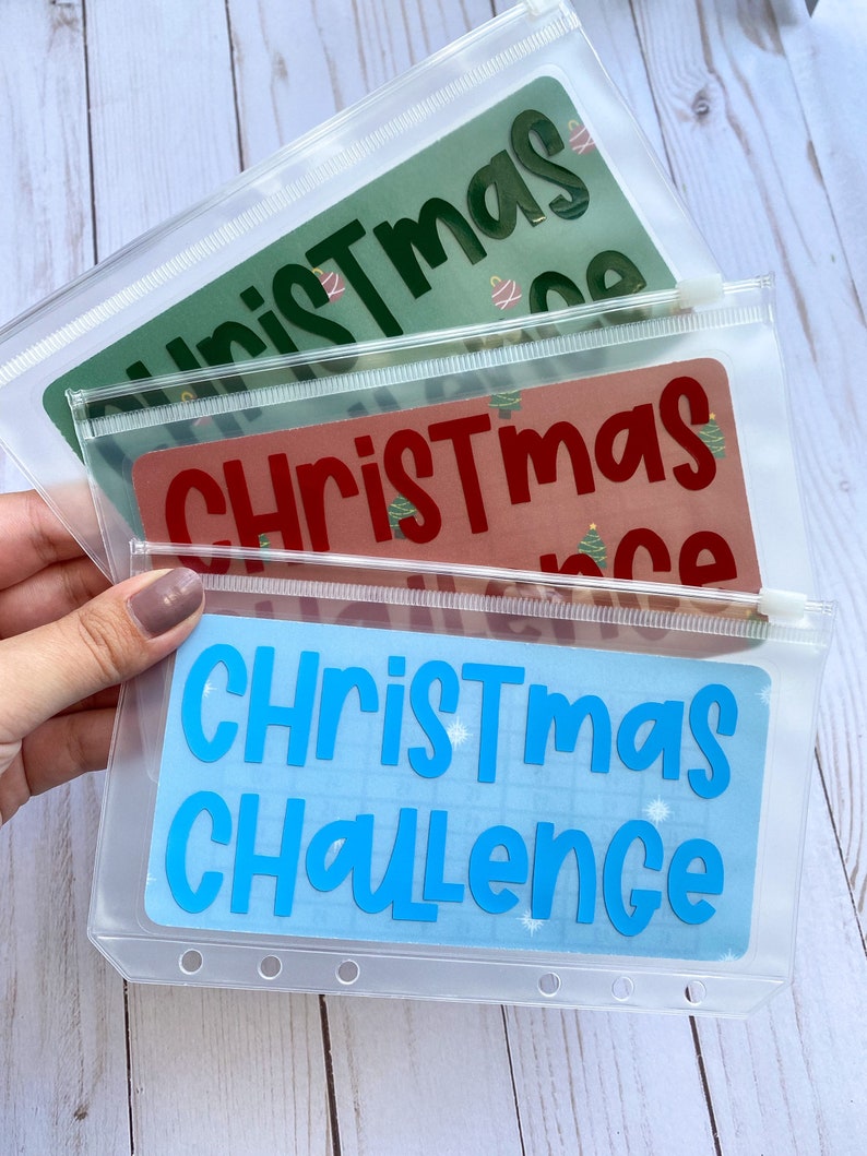 May include: Three clear plastic zipper pouches with different colored backgrounds and the text "Christmas" or "Christmas Challenge" in bold, white letters.