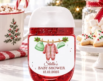 May include: A clear plastic hand sanitizer bottle with a white flip-top cap, filled with red liquid. The label features a watercolor illustration of a striped onesie and two green hats hanging on a clothesline, with the text Stella's BABY SHOWER 12.12.2025.