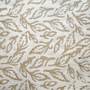May include: Close-up of a textured paper with a repeating pattern of stylized leaves in a light brown color. The leaves are arranged in a scattered, all-over design against a white background.