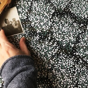 May include: A black and white photograph of two people, a woman and a child, with a floral pattern background.