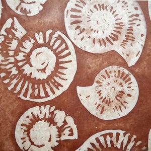 May include: A brown and white print featuring multiple stylized ammonite fossils. The fossils are white with detailed spiral patterns, set against a textured brown background. The design evokes a sense of natural history and ancient marine life.