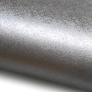 May include: Close-up of a textured, metallic silver surface. The material has a brushed appearance with subtle variations in tone and visible fine lines, creating a sense of depth and a tactile quality. The surface is slightly curved.