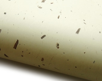 May include: Off-white handmade paper with embedded brown flecks. The paper is rolled, revealing its texture and color variations. The paper has a natural, organic aesthetic, suitable for crafts and stationery.
