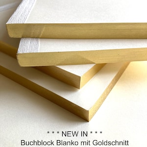 Può includere: Primo piano di quaderni vuoti impilati con bordi dorati. Le pagine sono bianche e i bordi sono di un colore oro brillante. Il testo "*** NEW IN *** Buchblock Blanko mit Goldschnitt" è in basso.