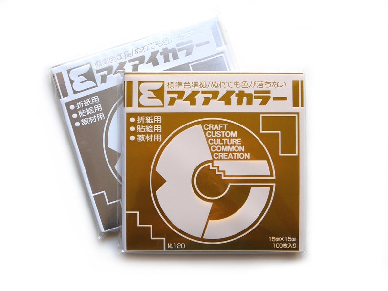 May include: Two packs of gold coloured paper. The front of the pack has the text "アイアイカラー" in Japanese. The text "CRAFT CUSTOM CULTURE COMMON CREATION" is also on the pack. The pack is labelled "No. 120" and "15cm x 15cm 100枚入り".