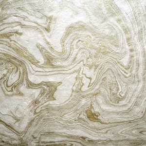May include: Close-up of a marbled paper design with swirling patterns in white and gold. The paper has a textured appearance, with gold veining creating a natural, flowing aesthetic. Suitable for craft projects, the design evokes a sense of luxury and artistry.