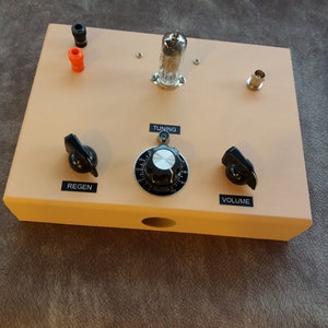 Puede incluir: Una caja beige con un tubo de vacío, una perilla de sintonización y dos perillas etiquetadas como "Regen" y "Volumen".