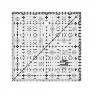 May include: A clear plastic quilting ruler with a diagonal line and a grid pattern. It is labeled "Itty-Bitty Eights - Square" and "Creative Grids".