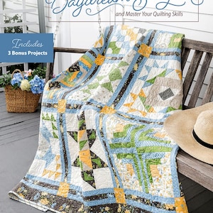 May include: A quilt pattern book titled "Stitch the Daydream Sampler" by Carolyn Beam. The book cover features a quilt with a blue, yellow, and green floral pattern. The quilt is draped over a wooden bench. The book includes 3 bonus projects and teaches quilting skills.