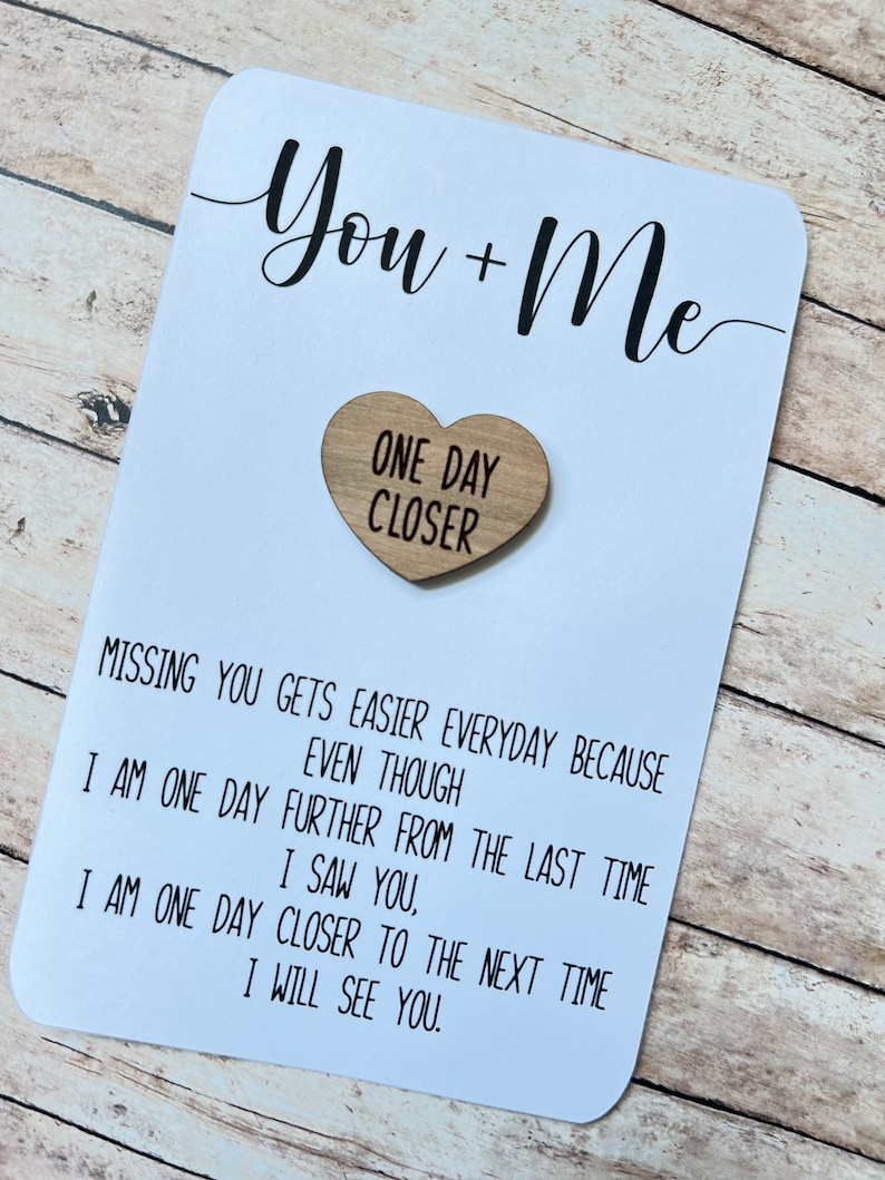 May include: White card with black text that reads "You + Me" and a wooden heart with the text "One Day Closer". The card reads "Missing you gets easier everyday because even though I am one day further from the last time I saw you, I am one day closer to the next time I will see you."